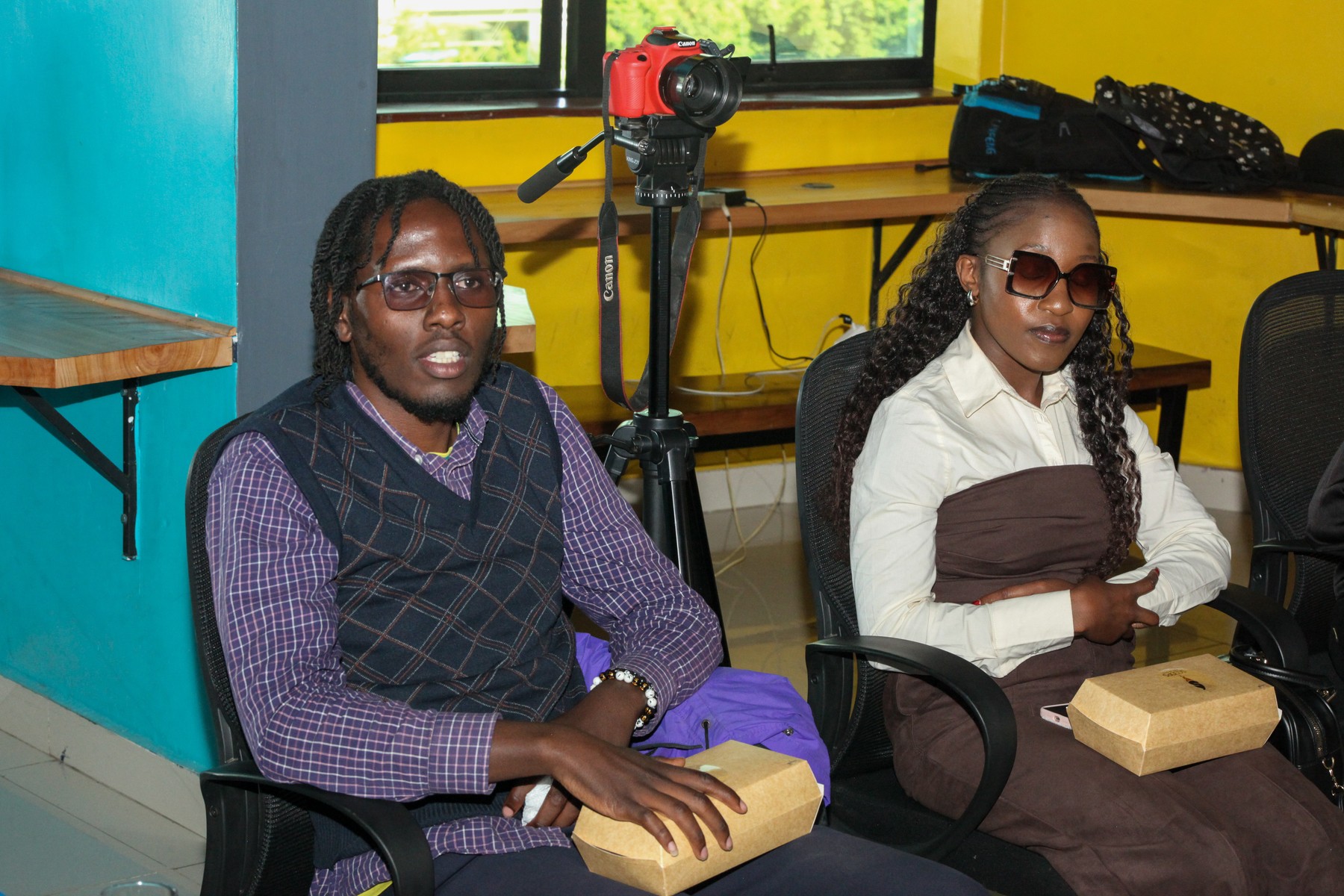 A man and a woman seated together with small boxes in their hands