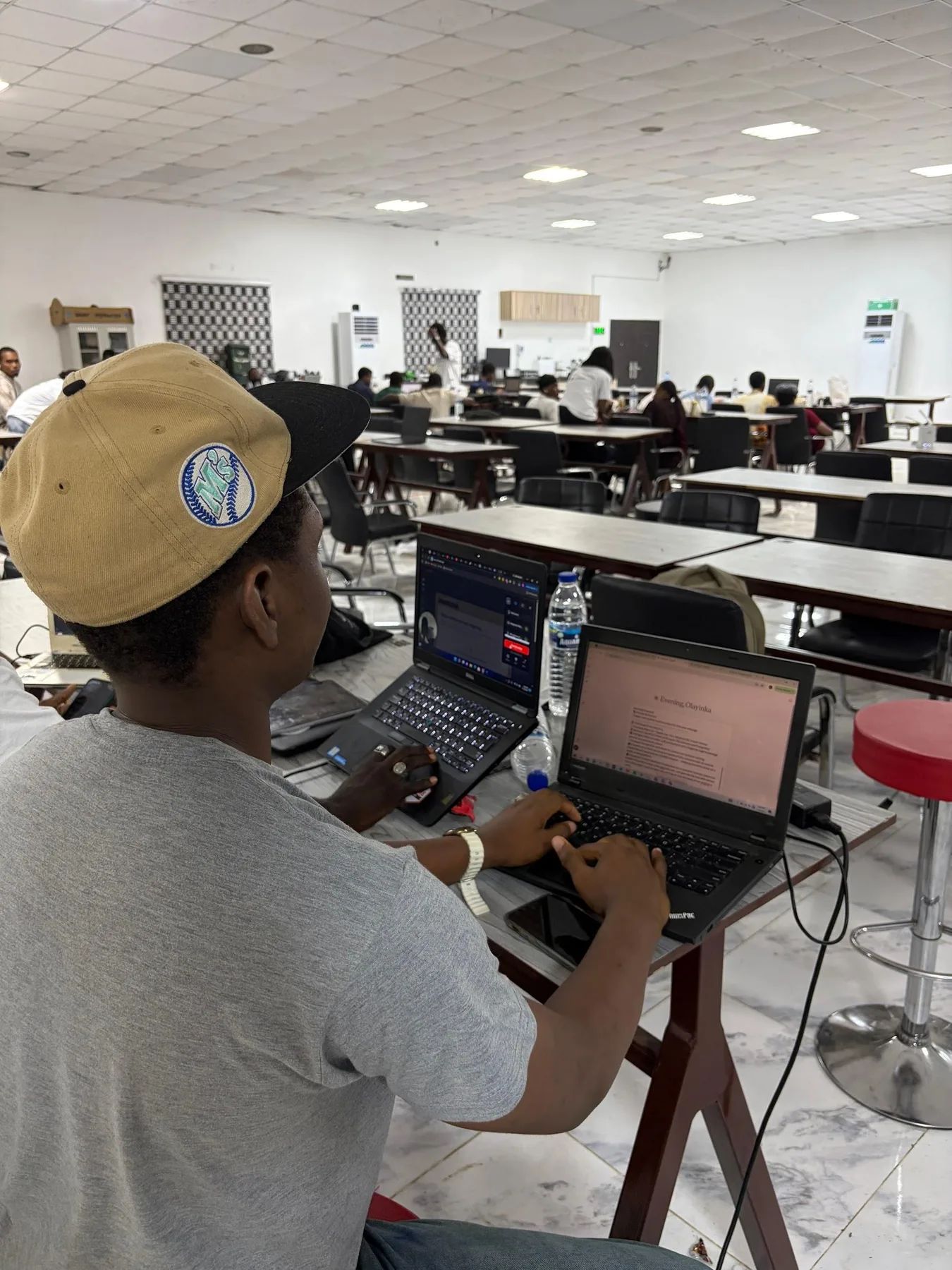 A builder in a cap writing code on a laptop